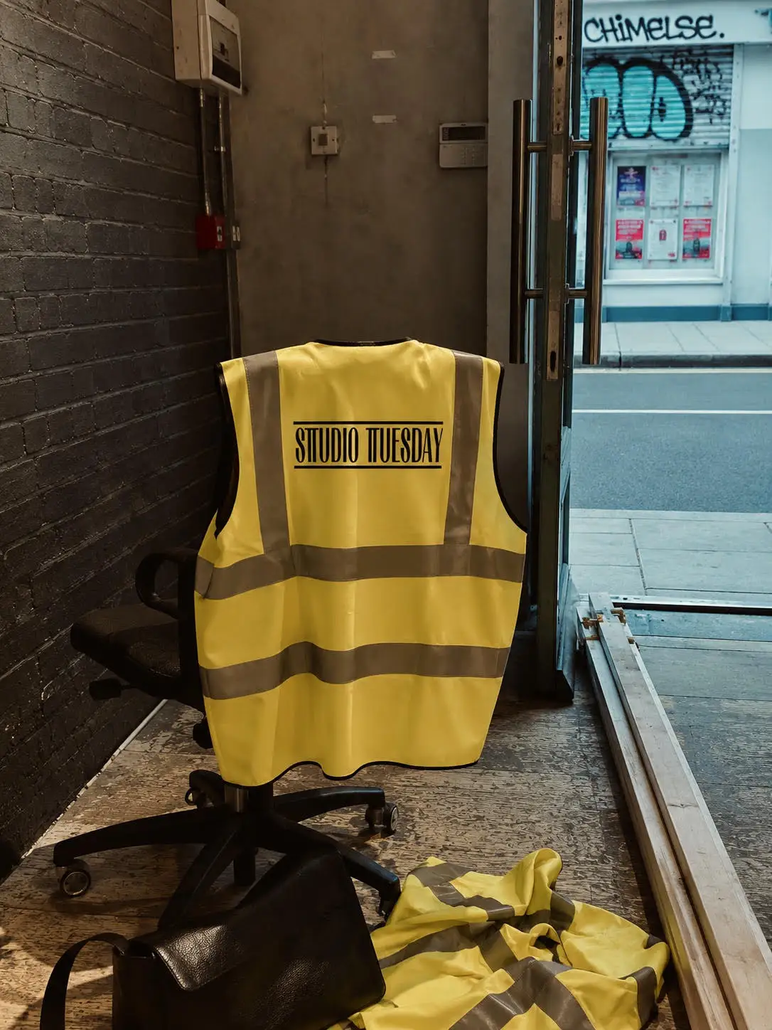 Studio Tuesday branded hi-vis vest hanging in the workshop doorway